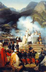 Painting by Horace Vernet titled First Mass in Kabylia, showing a Catholic priest elevating the Eucharist at an outdoor military altar surrounded by kneeling French Zouave soldiers and local Algerian observers in a mountainous landscape.